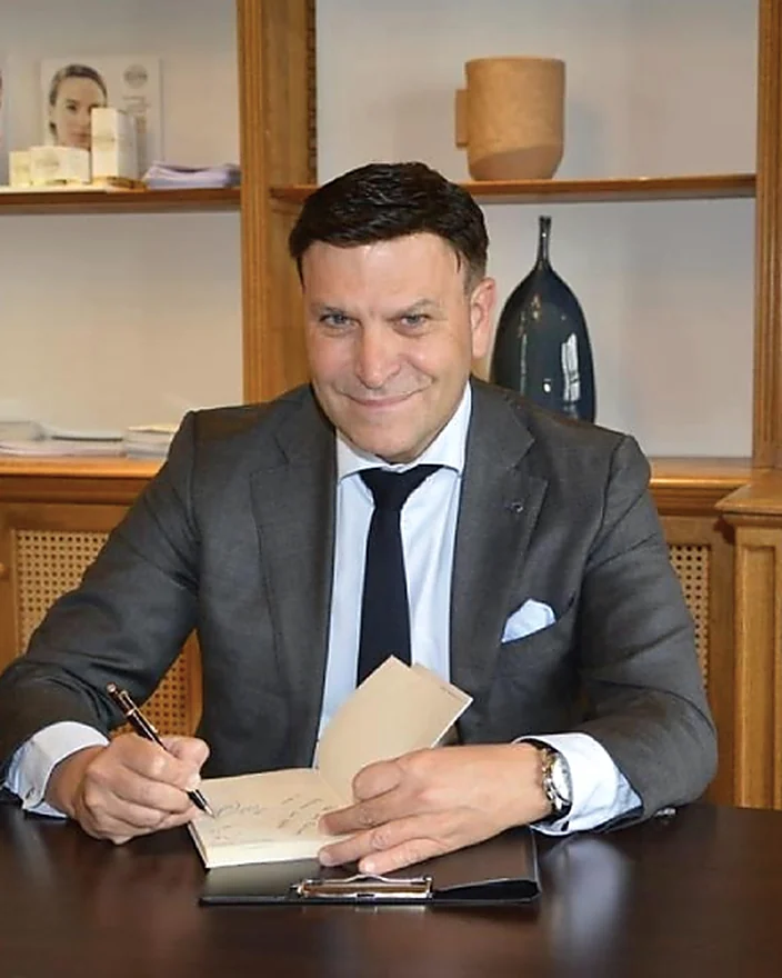 Massimo Romagnoli seduto a una scrivania mentre firma un documento.